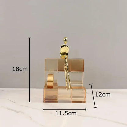 A sleek gold-toned minimalist golden thinker sculpture on a multi-tiered transparent acrylic thinker crystal base