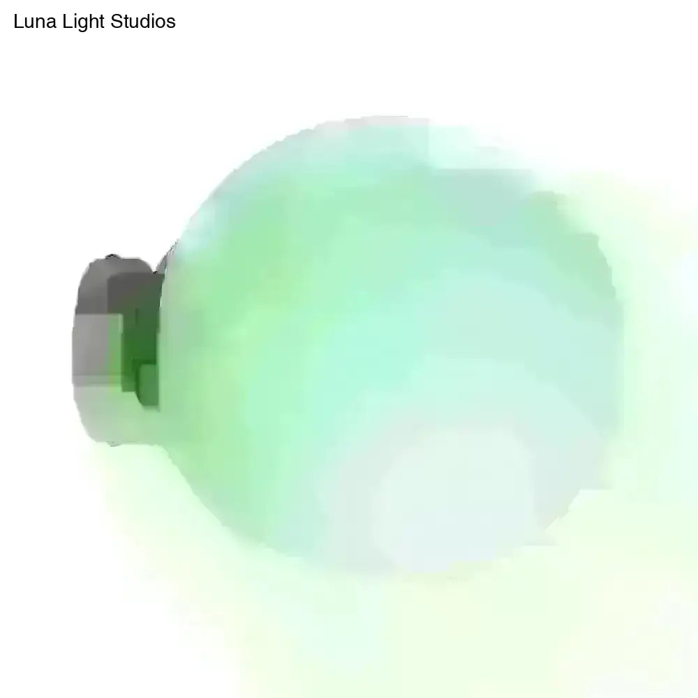 Minimalist green glass spherical sconce light with a translucent green bulb and dark gray base for balcony walls