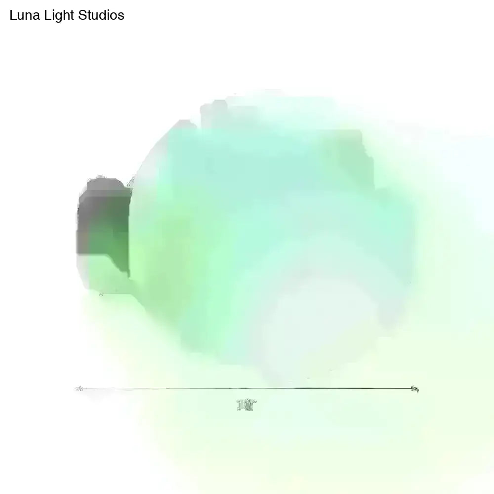A minimalist green glass spherical sconce light with a translucent mint-green glowing bulb and dark base for balcony wall use