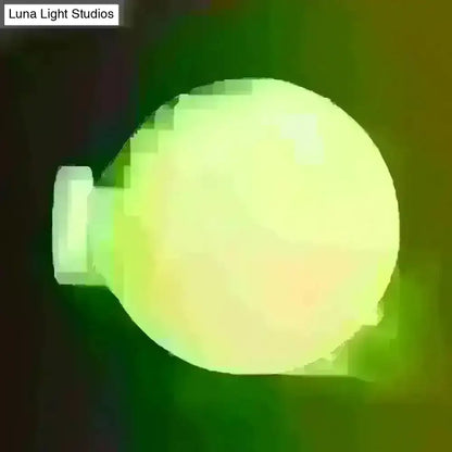 Minimalist green glass spherical sconce light with a glowing matte finish and white base for balcony wall mounting