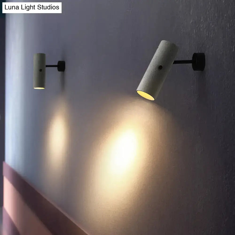 Minimalist grey led wall spotlight with cylindrical concrete sconces and black metal adjustable heads emitting warm light