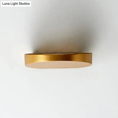 Gold-finished oval minimalist led wall sconce in grey aluminum designed for corridor lighting with visible light bulb