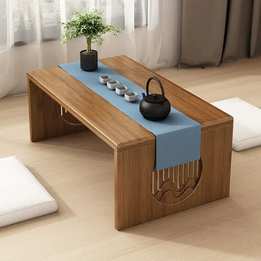 Minimalist light brown bamboo folding table with carved wave design and blue runner holding teapot and cups