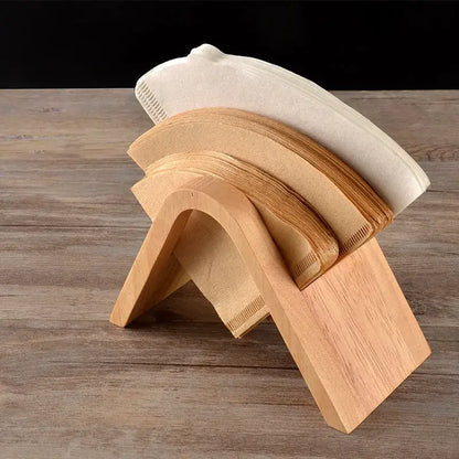 Minimalist light wood coffee filter holder with a curved a-frame design holding stacked paper coffee filters