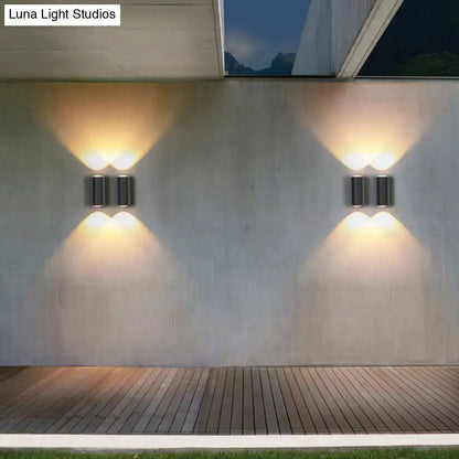 Minimalist matte black cylindrical wall light with dual warm-toned lights designed as an outdoor sconce light type