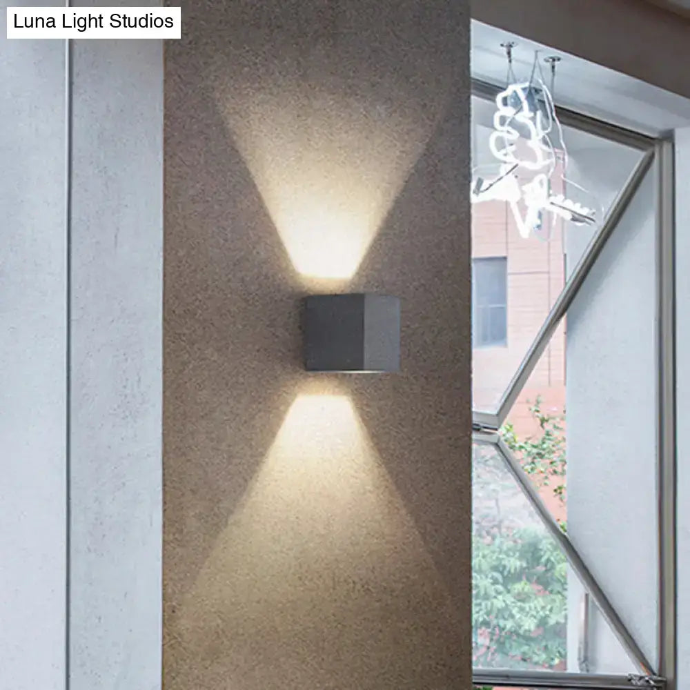 Minimalist matte gray concrete wall sconce with modern matte black square design casting warm angled light beams