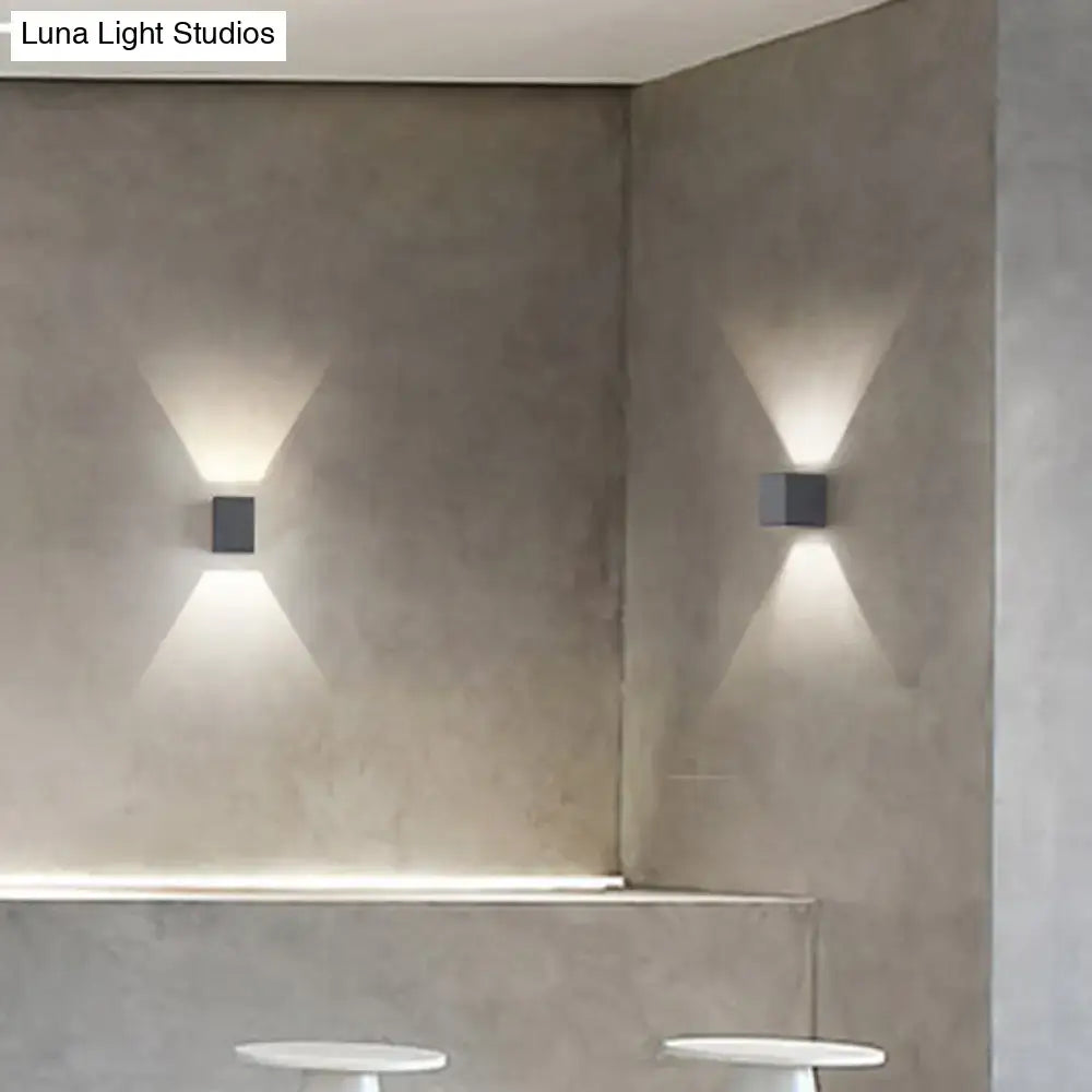 Modern black square minimalist wall sconces in matte gray concrete casting warm v-shape light for corridor use
