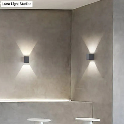 Modern black square minimalist wall sconces in matte gray concrete casting warm v-shape light for corridor use