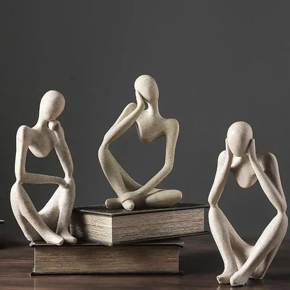 Three abstract beige ceramic thinker woman figurines in contemplative poses for minimalist living room decor