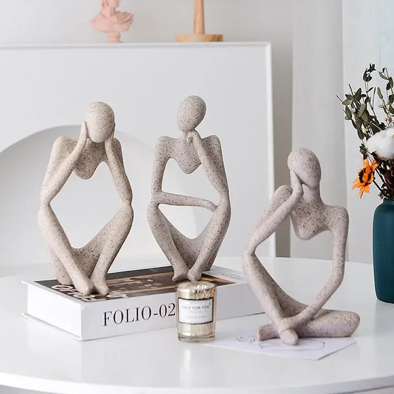 Three abstract thinker woman figurines in speckled beige resin with contemplative poses for minimalist living room decor