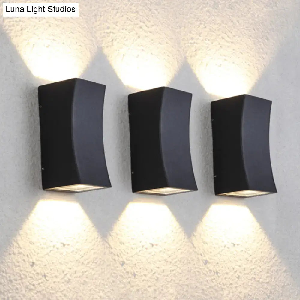 Three sleek black minimalist metal curved wall mount sconces emitting warm light for living room lighting