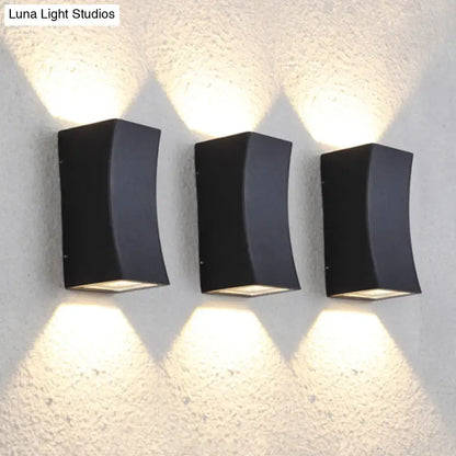 Three sleek black minimalist metal curved wall mount sconces emitting warm light for living room lighting