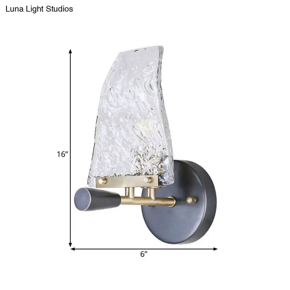 Minimalist sail glass wall light with textured clear glass shade brass accents and matte black base for bedroom use