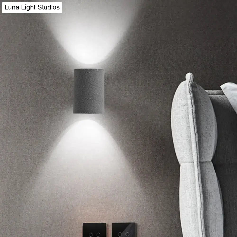 Minimalist speckled concrete led wall light with matte gray textured finish emitting two focused beams of light