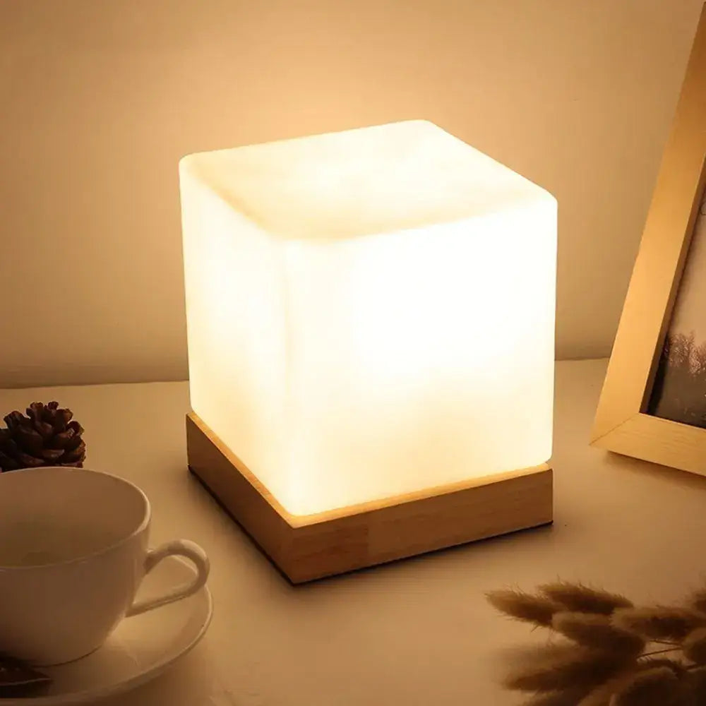 A warm glowing minimalist table lamp with frosted glass ball body and natural wood base for bedroom decorbites glass ball