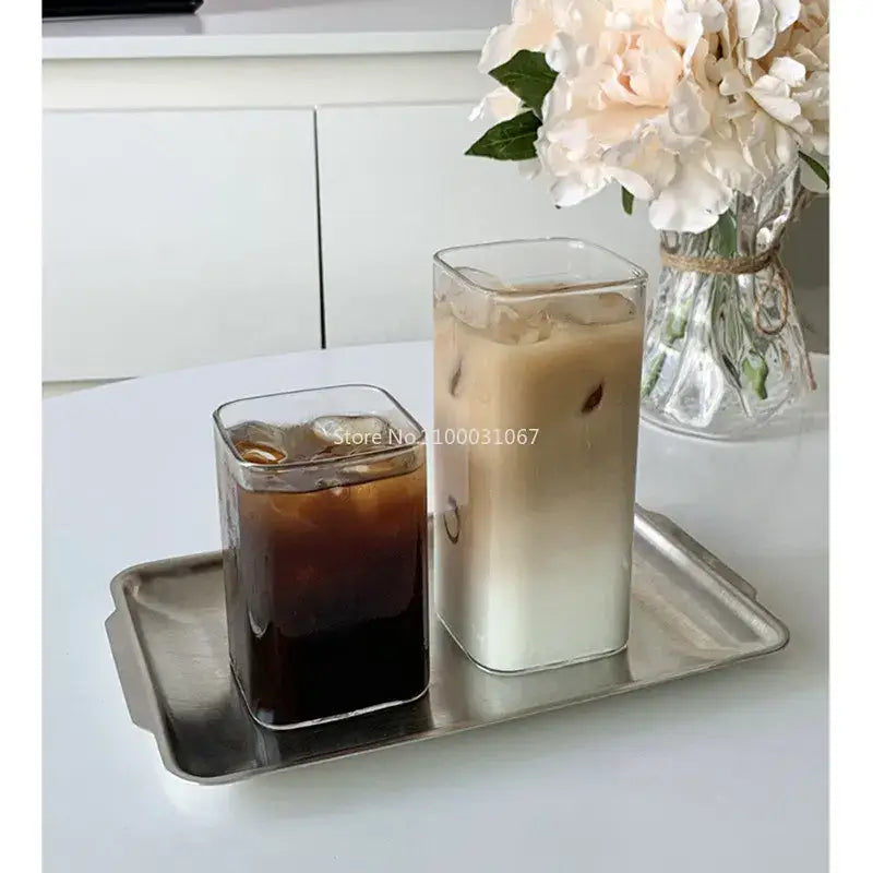 Minimalist rectangular glass juice cup filled with iced coffee and milk on a metallic tray for kitchen drinkware