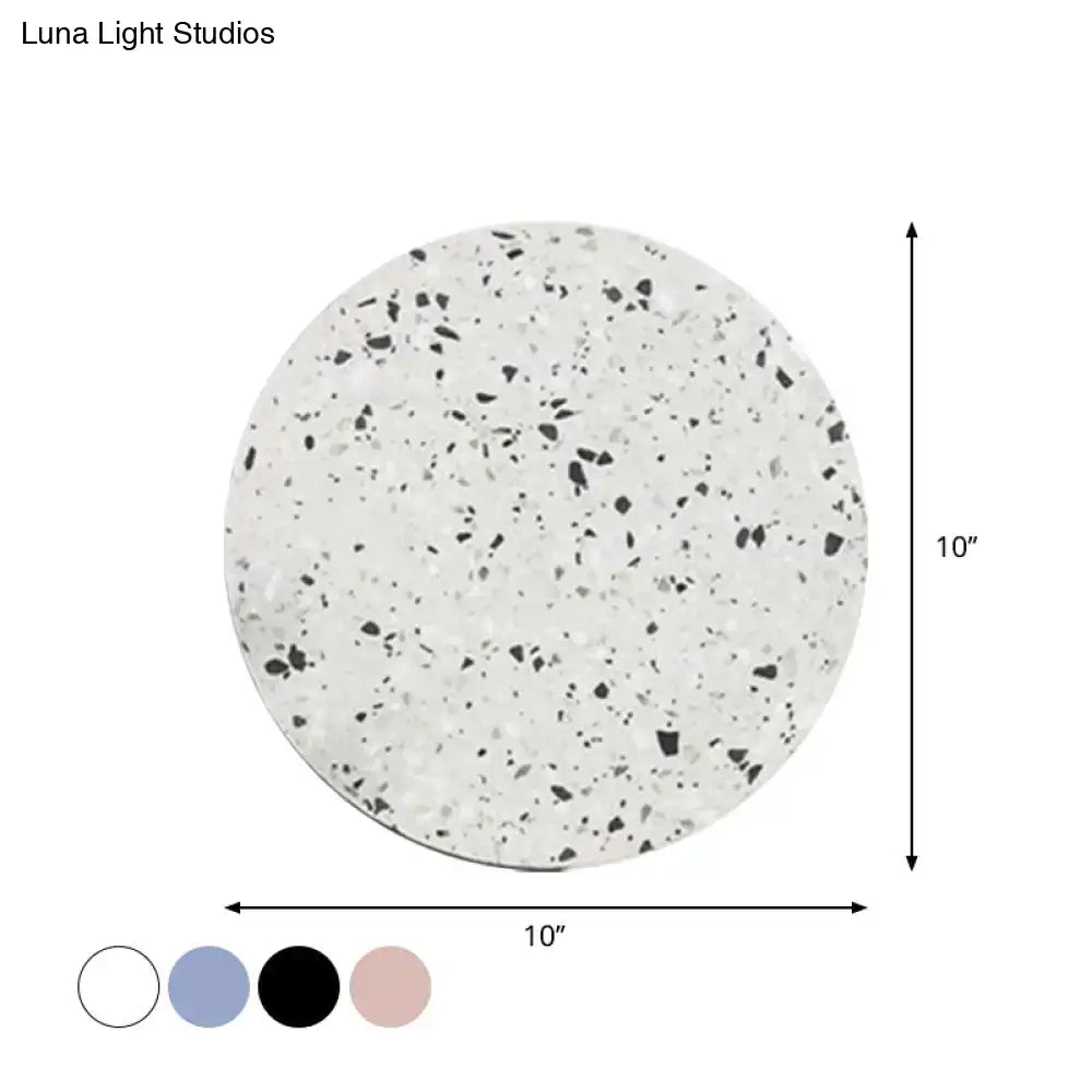 A 10-inch round terrazzo-style white and black speckled coaster complementing minimalist terrazzo round led wall sconce light