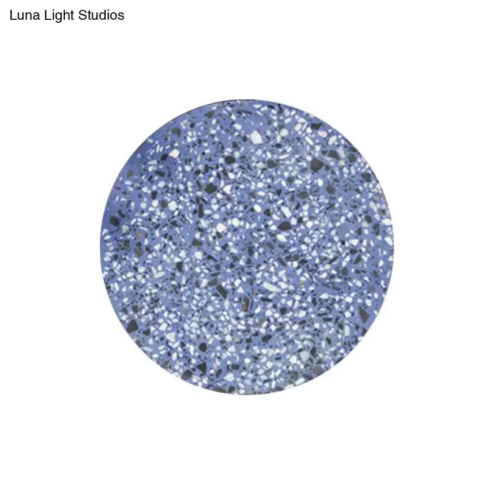 Minimalist terrazzo round led wall sconce in blue with a speckled white black and gray terrazzo coaster design