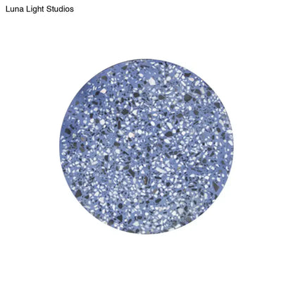 Minimalist terrazzo round led wall sconce in blue with a speckled white black and gray terrazzo coaster design