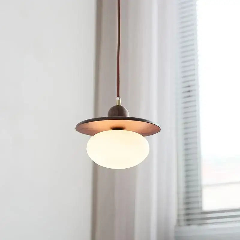 Minimalist walnut and brass glass led pendant lamp with a warm brass disc and white globe for dining room use