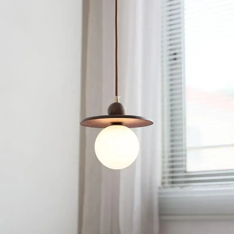 Minimalist walnut and brass glass led pendant lamp with warm brass disc shade and frosted globe bulb for dining room