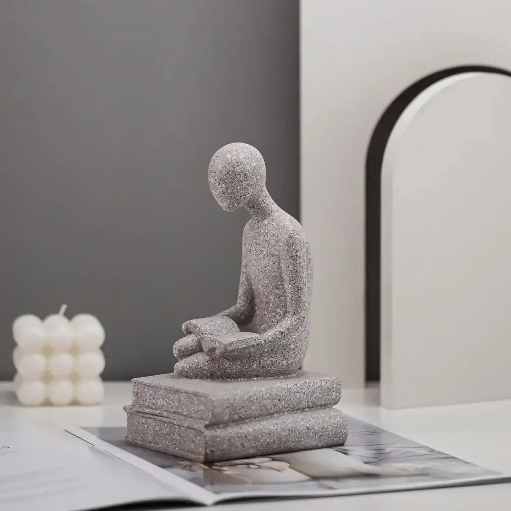 Gray textured resin abstract people decorbites statue of seated human reading on stacked books for living room decor