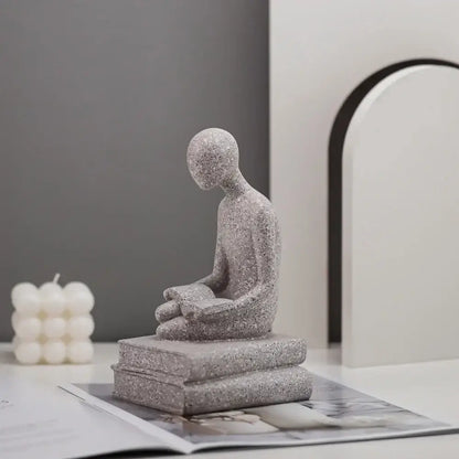 Gray textured resin abstract people decorbites statue of seated human reading on stacked books for living room decor