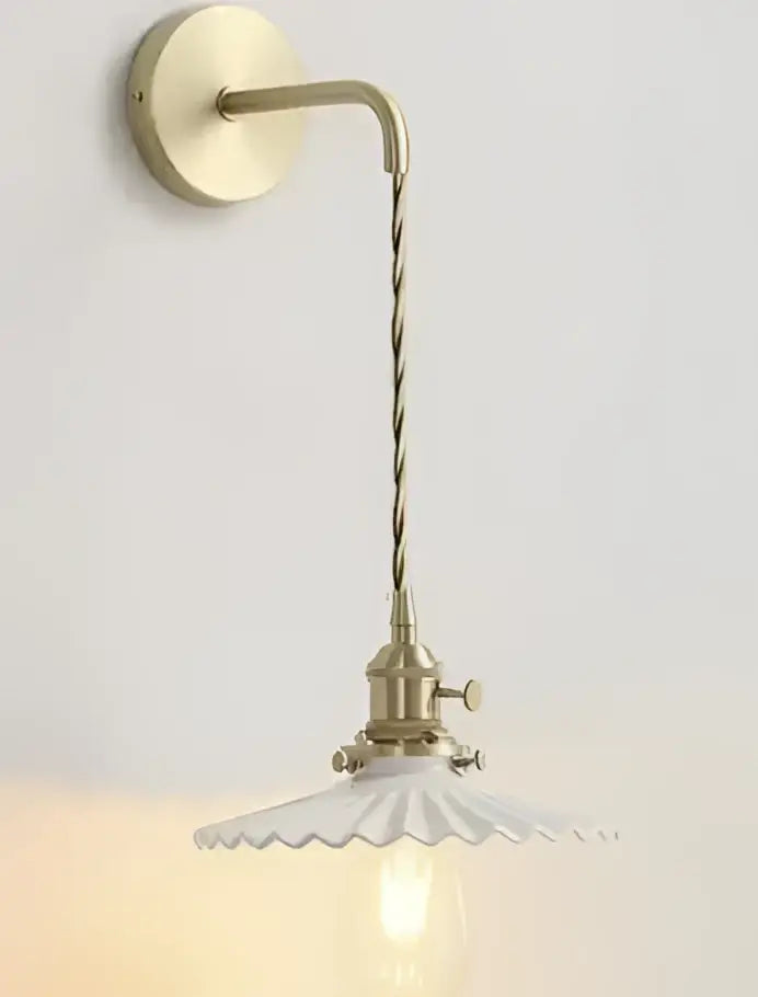 Brass-finished wall sconce with twisted cord and white scalloped glass shade complementing minimalist glass pendant light