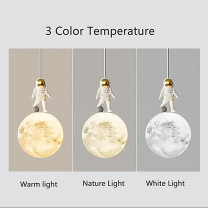 Minimalist white astronaut pendant light with gold helmet stands on textured moon lamp with three color settings decorbites astronaut pendant