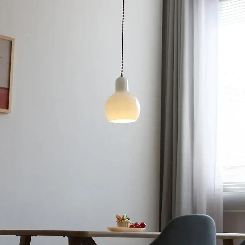 Minimalist white ceramic led pendant lamp with warm glow featuring smooth rounded shade and black braided cord for dining room
