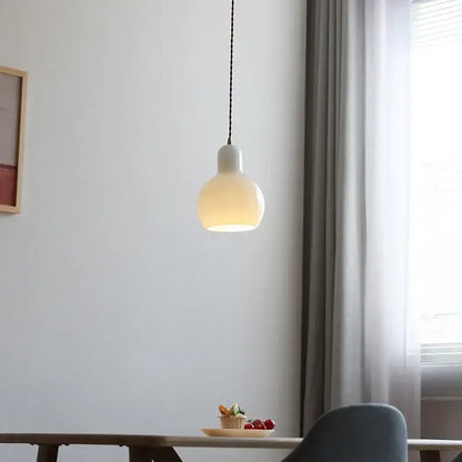 Minimalist white ceramic led pendant lamp with warm glow featuring smooth rounded shade and black braided cord for dining room