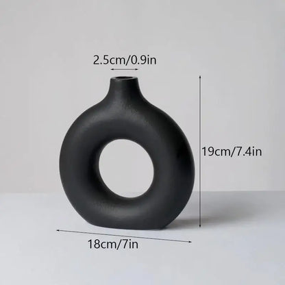 A sleek matte black ceramic donut vase by decorbites with modern ring design and smooth rounded contours for minimalist decor