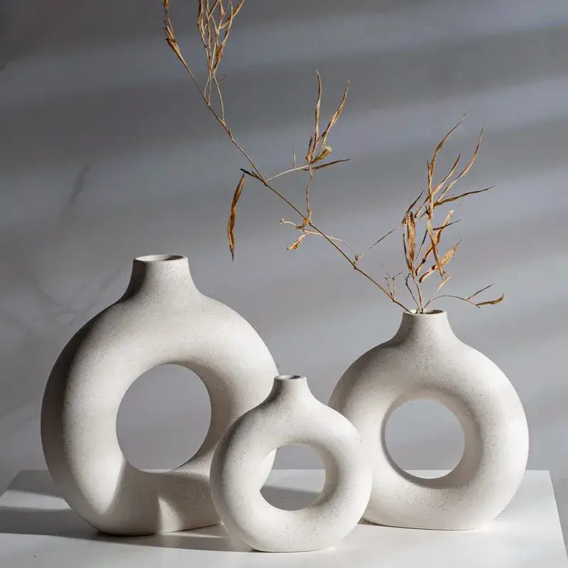 Three minimalist white decorbites ceramic donut vases with circular cutouts in varying sizes for living room decor