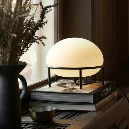 Minimalist white glass ball table lamp with a warm glow and black metal frame perfect for bedroom decorbites glass ball table