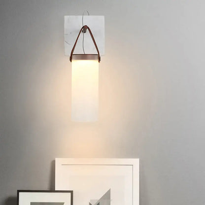 Minimalist wall light with white glass shade and leather strap mounted on marble plate for bedroom use