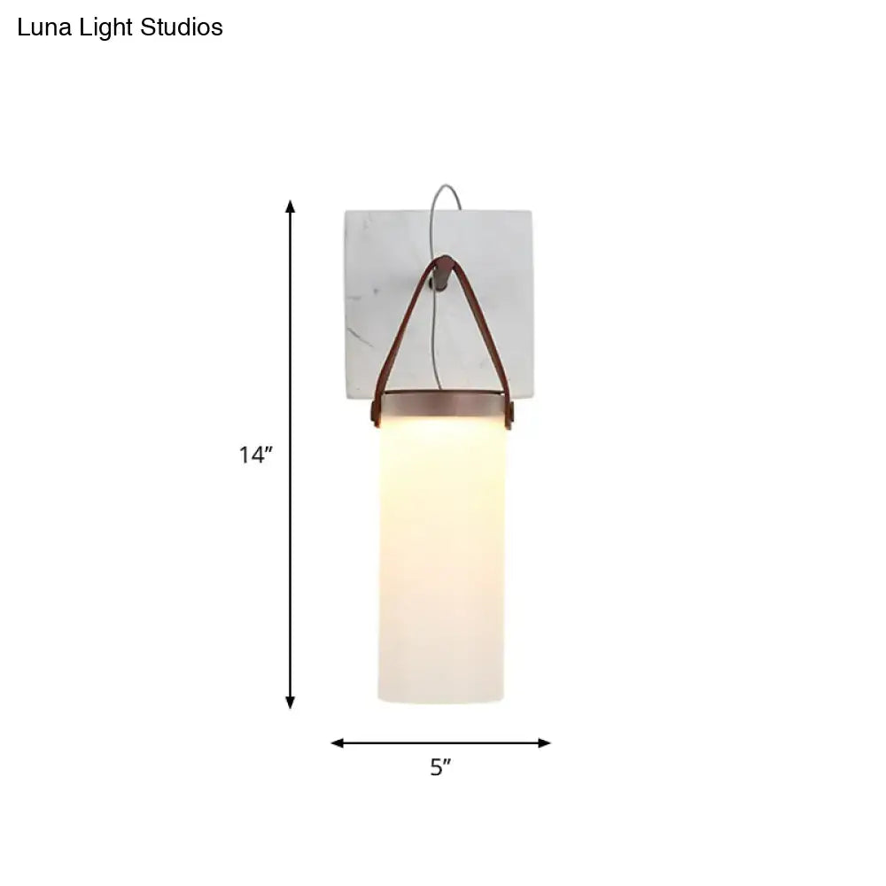 Minimalist white glass wall light with leather strap featuring frosted glass and copper-toned metal for bedroom use