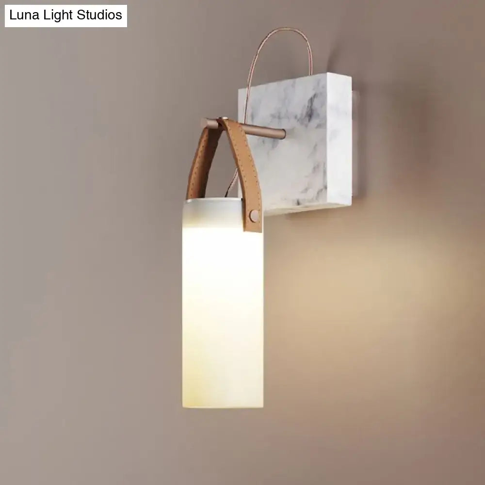 Minimalist wall light with white glass shade, marble backplate, copper accents, and leather strap for bedroom