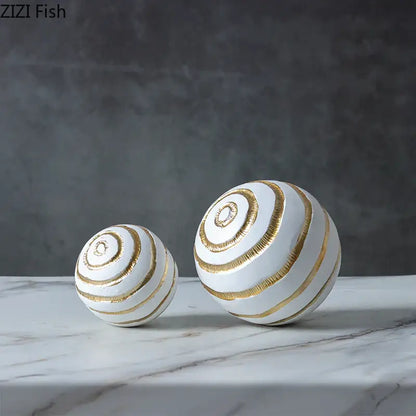 Minimalist white ceramic spheres with gold spiral stripes as geometric desk decoration and golden texture ball accents