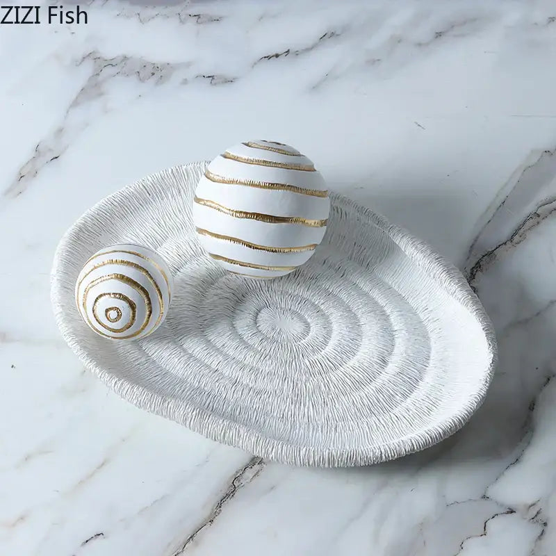 Minimalist white ceramic tray with textured concentric circles and gold stripes holding two golden texture balls for desk decoration
