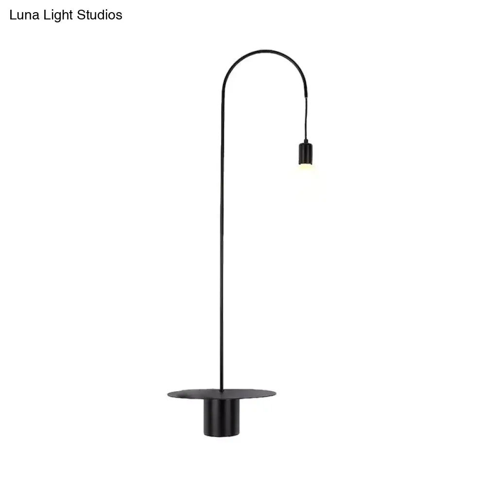 Black minimalist floor lamp with curved arm and cylindrical shade designed as a wall sconce wall light for bedroom use