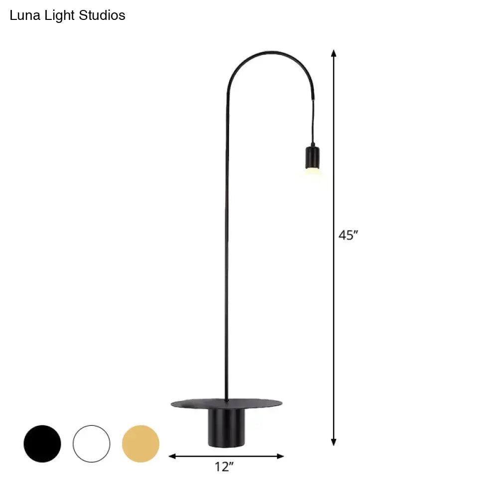 Black matte-finished floor lamp with slender curved arm and circular base complementing minimalist wall light sconce