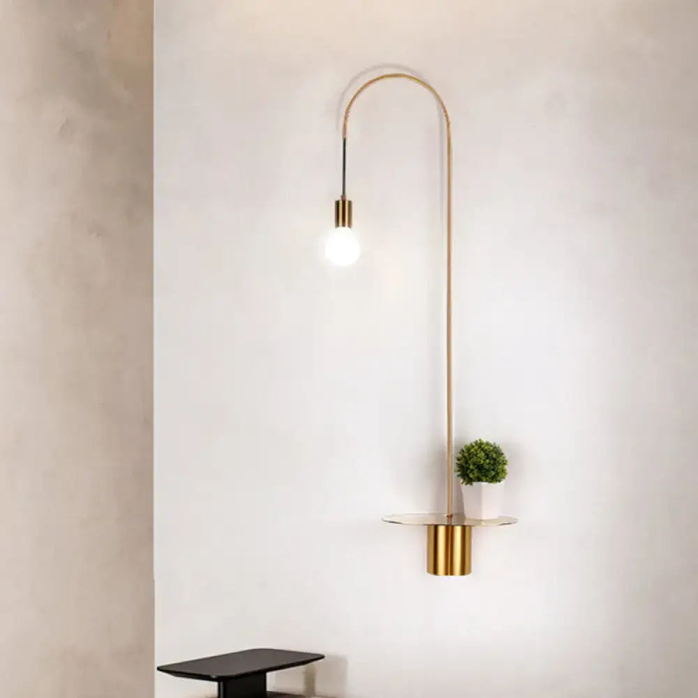 Minimalist gold-toned arched wall sconce with integrated glass shelf and green plant as a stylish wall light