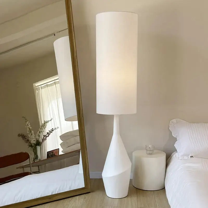 A minimalist white led floor lamp with a sleek cylindrical design and sculpted tapered base for living room use