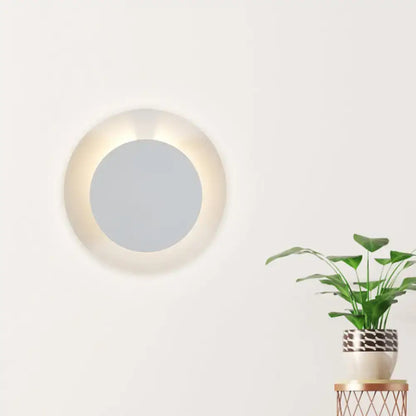 Minimalist white led circular wall sconce lamp with softly glowing illuminated frame for bedroom lighting