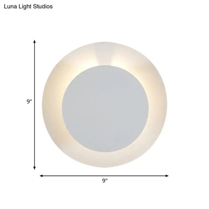 Minimalist white led wall sconce lamp with frosted glass ring and central mirror emitting soft warm light for bedroom use