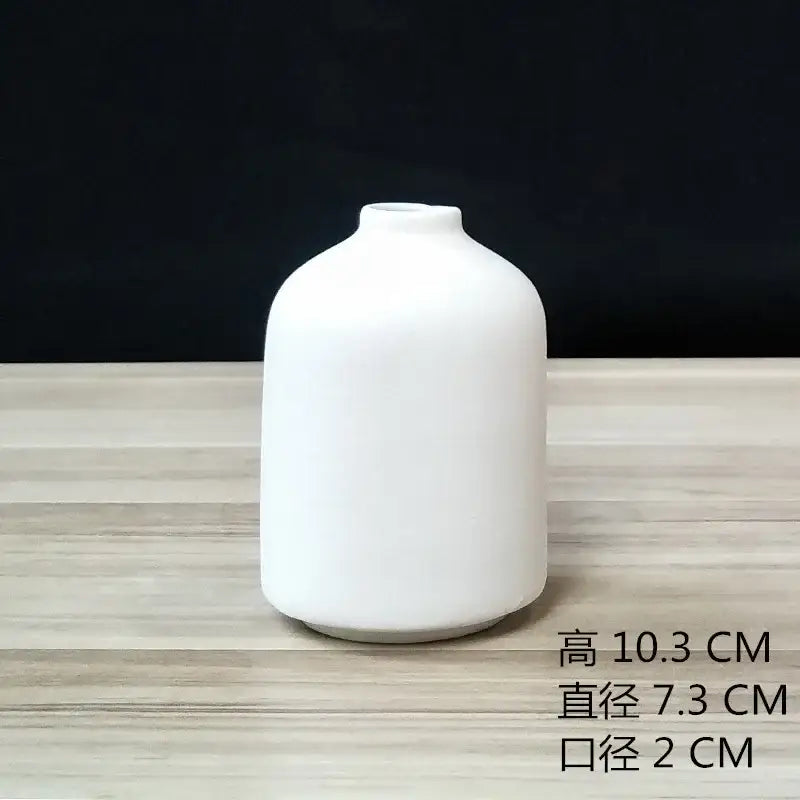 A sleek minimalist white decorbites ceramic vase with rounded body and narrow neck for dining room decor