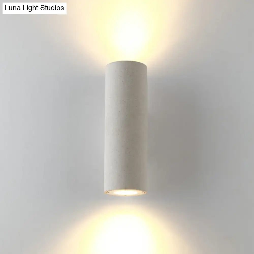Minimalist white terrazzo stair wall sconce with compact fixture height and matte finish emitting warm ambient light