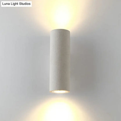 Minimalist white terrazzo stair wall sconce with compact fixture height and matte finish emitting warm ambient light