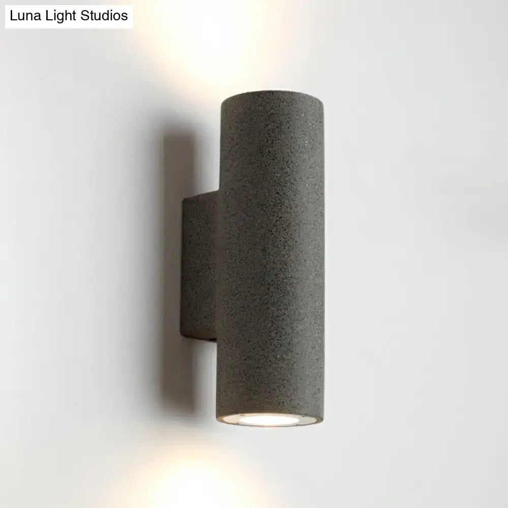 Gray textured cylindrical wall sconce with sleek modern design and compact fixture height for minimalist terrazzo stairs