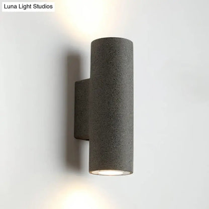Gray textured cylindrical wall sconce with sleek modern design and compact fixture height for minimalist terrazzo stairs